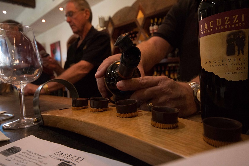 A vintner pours a flight of red wine.